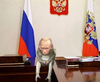 a monkey sitting on a desk in front of russian flags