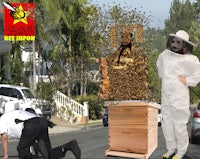 a man in a bee suit standing next to a bee box