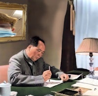 a picture of a man writing in front of a mirror