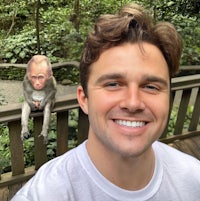 a man smiling with a monkey on a bridge