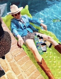 a man in a cowboy hat is laying in a pool