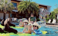 a group of people in a pool with zebras in the background