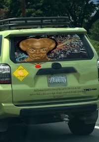 the back of a green suv with a picture of an alien on it