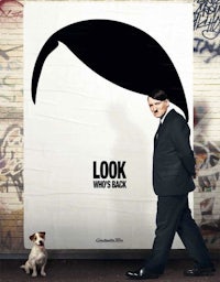 a man in a suit and a dog standing next to a poster for look who's back