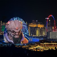 las vegas at night with an image of a demon in front of the city