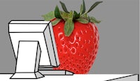 a strawberry sitting in front of a computer